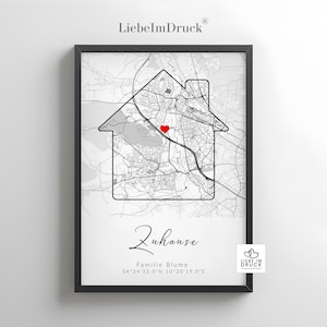 May include: Framed black and white map print featuring a house-shaped outline with a red heart marking a location. The print includes the word "Zuhause" and the text "Familie Blume" with coordinates.