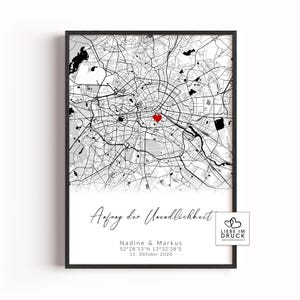 Könnte beinhalten: Gerahmter Schwarz-Weiß-Karten-Druck einer Stadt, mit einem roten Herzen, das einen Ort markiert. Der Druck enthält den Text "Anfang der Unendlichkeit", Namen und ein Datum. Ein kleines Logo befindet sich unten rechts.