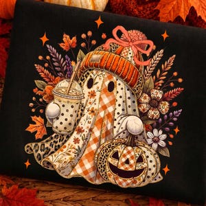 May include: A black sweatshirt featuring a graphic of a ghost wearing an orange knit hat with a bow. The ghost holds a polka-dot iced coffee cup and a pumpkin with a plaid pattern. The design includes autumn leaves, flowers, and star shapes.