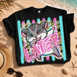 Puede incluir: Camiseta negra con un diseño de hámster de dibujos animados. El diseño presenta la palabra "LATER" en rosa y blanco, con rayas verticales azules y rosas. El hámster es gris, blanco y rosa, con la palabra "ZAP!" en amarillo.
