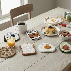 Peut inclure: Ensemble de dessous de verre faits à la main en forme d'aliments, dont un biscuit, du pain grillé, un œuf et un avocat. Une tasse à café blanche et un verre de jus d'orange sont également sur la table en bois. Les dessous de verre sont conçus pour ressembler à des articles de petit-déjeuner.