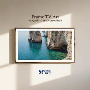 May include: A framed print depicting a coastal scene with turquoise water and large rock formations. The artwork is labelled "Frame TV Art" with "4K Quality | 3840x2160 Pixels". The logo "Unfold & Fly" is in the lower left corner.