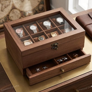May include: A wooden watch box with a glass top, showcasing several wristwatches. The box has a drawer with jewelry. The box is made of dark brown wood and has a brass clasp and drawer pull.