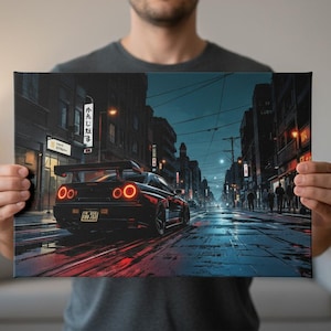 Op de afbeelding: Een canvas print met een zwarte sportwagen met rode achterlichten die 's nachts door een stadsstraat rijdt. Het kunstwerk toont een gedetailleerde illustratie van de auto en de stedelijke omgeving, met de nadruk op verlichting en reflecties.