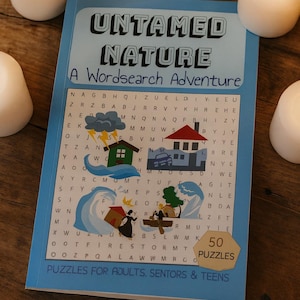 May include: A blue word search puzzle book titled "Untamed Nature" with 50 puzzles. The cover features illustrations of a house, car, and people in a boat. White candles are in the background.