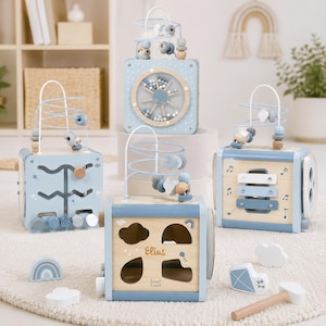 May include: A selection of baby activity cubes in light blue and natural wood. The cubes feature bead mazes, shape sorters, and musical elements. The cubes are decorated with clouds, rainbows, and the name "Elias". The toys are designed to stimulate early learning.
