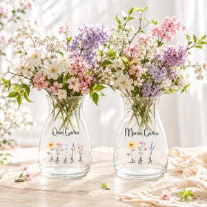 Puede incluir: Dos jarrones de cristal transparente con bordes acampanados, llenos de ramos de flores blancas, rosas y moradas. El jarrón izquierdo presenta el texto Omas Garten con cinco pequeñas ilustraciones florales y nombres. El derecho muestra Mamas Garten con tres ilustraciones florales y nombres.