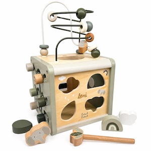 May include: A wooden activity cube featuring a bead maze, shape sorter, and pounding bench. The cube is painted in neutral tones of green, beige, and natural wood. Includes wooden shapes, a hammer, and the name "Leni".