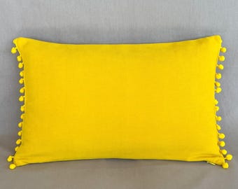 Funda de cojín de terciopelo amarillo con pompón, cojín decorativo pequeño y colorido.