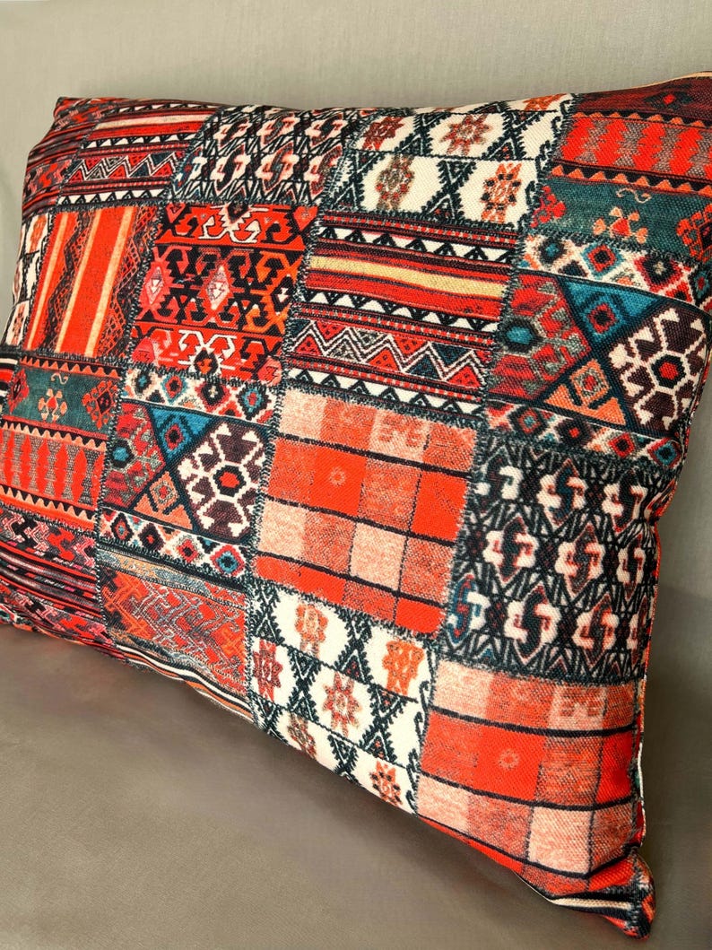Puede incluir: Coj&iacute;n rectangular decorativo con dise&ntilde;o de patchwork. El coj&iacute;n presenta una vibrante mezcla de patrones en rojo, naranja, turquesa y negro. El dise&ntilde;o incluye formas geom&eacute;tricas, rayas y motivos florales, creando una apariencia texturizada y colorida.