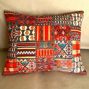 Puede incluir: Coj&iacute;n decorativo rectangular con dise&ntilde;o de patchwork. El coj&iacute;n presenta una vibrante mezcla de patrones geom&eacute;tricos rojos, naranjas y negros. Es un elemento de decoraci&oacute;n del hogar acogedor, perfecto para a&ntilde;adir un toque de color y textura.