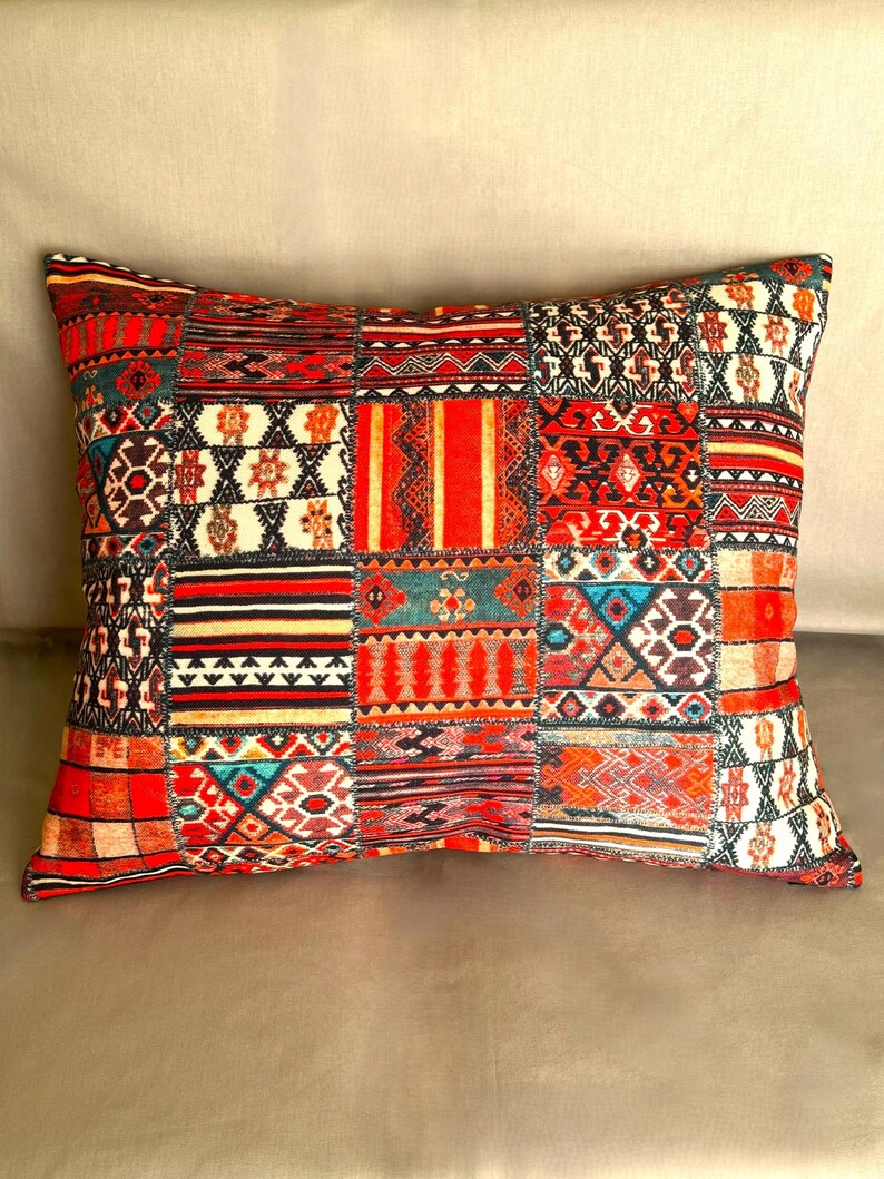 Puede incluir: Coj&iacute;n decorativo rectangular con dise&ntilde;o de patchwork. El coj&iacute;n presenta una vibrante mezcla de patrones geom&eacute;tricos rojos, naranjas y negros. Es un elemento de decoraci&oacute;n del hogar acogedor, perfecto para a&ntilde;adir un toque de color y textura.