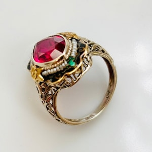 Peut inclure: Une bague en filigrane avec une grande pierre précieuse rouge sertie dans un sertissage or et argent. La bague est marquée "O-F".