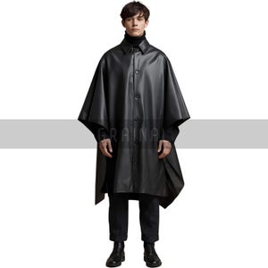 May include: A black leather cape with a button-down front and a collar. The cape is worn over a black turtleneck and pants. The image has the word "GRAINAL" printed on the cape.