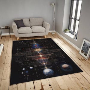 May include: A large, rectangular black rug featuring a detailed illustration of the solar system and celestial bodies. The design includes planets, orbits, and cosmic elements in various colors. The rug is placed on a wooden floor, near a gray sofa.