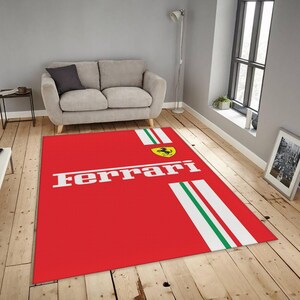 Könnte beinhalten: Ein roter rechteckiger Teppich mit dem Wort "Ferrari" in weißen Blockbuchstaben. Der Teppich hat weiße Streifen mit grünen Akzenten und ein gelbes Emblem mit einem schwarzen Pferd. Der Teppich liegt auf einem Holzboden.