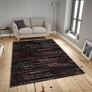 Puede incluir: Una alfombra rectangular con un diseño que simula código informático en rojo, verde y blanco sobre un fondo oscuro. La alfombra está colocada sobre un suelo de madera en un salón, con un sofá gris y una ventana al fondo.