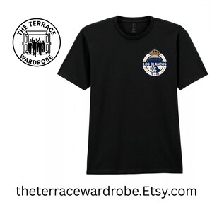 May include: Black t-shirt with a small, circular emblem featuring a crown, building, and text "LOS BLANCOS 19-02." The shirt also has a logo on the upper left with the text "THE TERRACE WARDROBE." The website address is theterracewardrobe.Etsy.com.