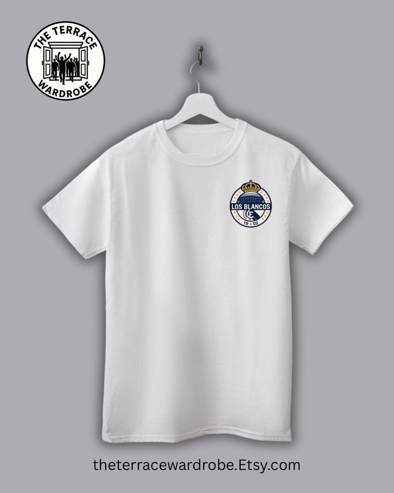 May include: White crew neck t-shirt with a small, circular emblem on the left chest. The emblem features a crown above the words "LOS BLANCOS" in a navy blue and gold design. The Terrace Wardrobe logo is at the top left.
