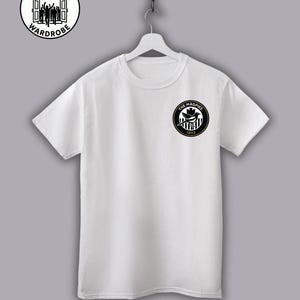 May include: White t-shirt with a black and white circular logo on the chest that reads "THE MAGPIES 1892". The shirt also has a circular logo on the upper left that reads "THE TERRACE WARDROBE". The website address is printed at the bottom.