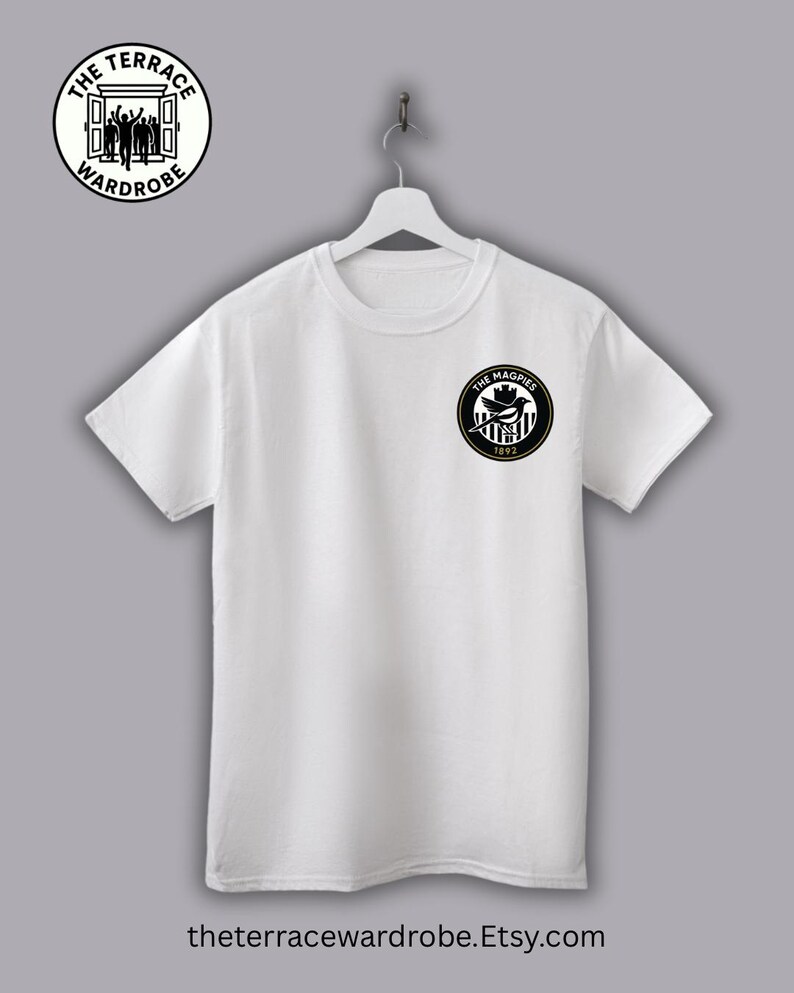 May include: White t-shirt with a black and white circular logo on the chest that reads "THE MAGPIES 1892". The shirt also has a circular logo on the upper left that reads "THE TERRACE WARDROBE". The website address is printed at the bottom.