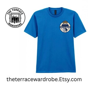 May include: A bright blue t-shirt with a crew neck and short sleeves. The shirt features a circular emblem with the text "LOS BLANCOS" and a crown design. The text "19-02" is also visible. The text "theterracewardrobe.Etsy.com" is at the bottom.