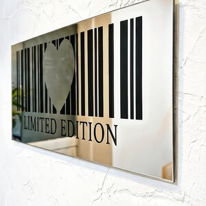 May include: A rectangular mirror with a silver frame. The mirror features a barcode design with a heart-shaped cutout in the center. The words "LIMITED EDITION" are printed in black below the barcode.