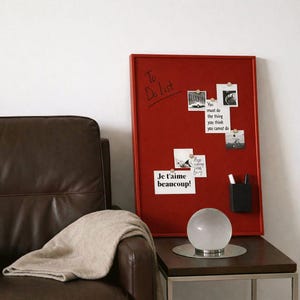 May include: A red framed bulletin board with notes and a pen holder. The board has the words "To Do List" written on it. A clear glass sphere lamp sits on a dark brown table. A brown leather chair is to the left.