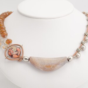 May include: A multi-strand necklace featuring brown, beige and white beads, a large agate pendant and silver accents.