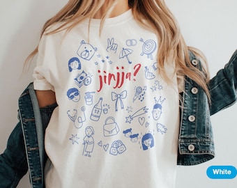 May include: White t-shirt with a blue and red graphic design. The design includes various doodles and the word "jinjja?" in red. The shirt features a crew neck and short sleeves.