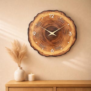 Puede incluir: Un reloj de pared redondo de madera, con un patrón de vetas naturales. La esfera tiene números blancos y manecillas doradas. El reloj está montado en una pared beige. El diámetro del reloj es de aproximadamente 30 cm.