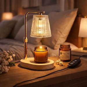 Könnte beinhalten: Eine goldfarbene Lampe mit geripptem Glasschirm beleuchtet einen Holzsockel mit einer brennenden Kerze. Zwei weitere Kerzen und ein Glas Duftkerze stehen ebenfalls auf dem Holztisch. Ein Bedienfeld ist mit der Lampe verbunden.