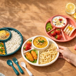 Puede incluir: Imagen colorida de platos divididos llenos de varios alimentos, incluyendo arroz, sopa, verduras, frutas y pasta. Los platos son en tonos de verde azulado, rosa y blanco, con utensilios a juego. También se ve un vaso de agua con limón.