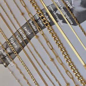 Op de afbeelding: Een verzameling gouden kettingen in diverse stijlen, waaronder parel, lip, figaro, rank, sierlijk, gedraaid, kralen, schakelketting, cubaanse, 3 mm visgraat, dunne visgraat en touw. Bovenaanzicht.