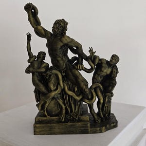 Peut inclure: Sculpture de couleur bronze représentant une figure musclée avec une barbe, entourée d'autres figures, toutes enchevêtrées avec des serpents. La sculpture est sur une base rectangulaire et présente des détails complexes.