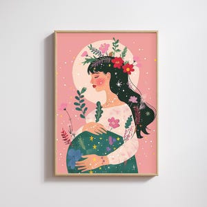 May include: A framed art print featuring a woman with long black hair adorned with flowers. She cradles her pregnant belly, which is decorated with flowers and stars. The background is a soft pink with a white circle and floral accents.