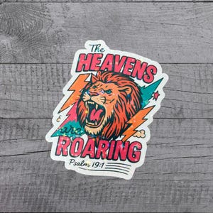 May include: A sticker featuring a roaring lion with orange and teal fur, surrounded by orange lightning bolts. The text "The Heavens are Roaring" is in pink and teal, with "Psalm 19:1" below.