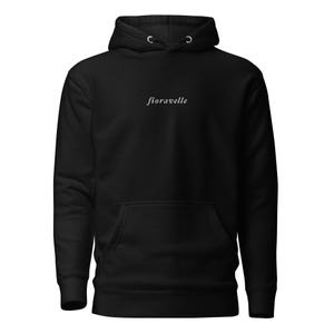 May include: Black hoodie with a drawstring hood and a front pocket. The word "fioravelle" is printed in a cursive font across the chest. The hoodie is made of a soft material.