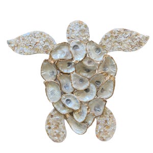 May include: A sea turtle wall art piece crafted from iridescent oyster shells. The shell of the turtle is composed of overlapping whole oyster shells with gold-painted edges, while the head and flippers are filled with crushed shell fragments.