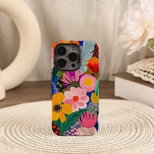 Puede incluir: Una funda para smartphone con un vibrante patrón floral multicolor. El diseño incluye flores estilizadas en tonos amarillos, rosas, naranjas y rojos, sobre un fondo azul profundo con follaje verde y diversas texturas de puntos.