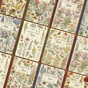May include: A collection of composition notebooks featuring vintage-style botanical illustrations of various wildflowers and garden plants. Each notebook cover displays a white rectangular label with the text Composition Notebook and a name.