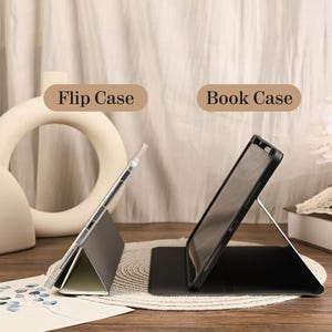 May include: A side-by-side comparison of two tablet covers. On the left, a gray flip case with a clear shell is propped up. On the right, a black book case with a dark frame is standing upright. The text Flip Case and Book Case appear above them.