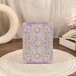 May include: A rectangular e-reader case featuring a stained glass style design with pastel pink, blue, and purple hues. The pattern includes central sun and moon faces, surrounded by intricate floral vines, leaves, and geometric star motifs.