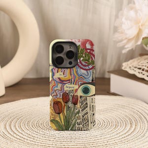 Puede incluir: Funda de teléfono con un diseño de collage con tulipanes, un ojo y elementos arquitectónicos. La funda tiene un borde color crema y la palabra "layers" es visible. El diseño incorpora una mezcla de colores y texturas.