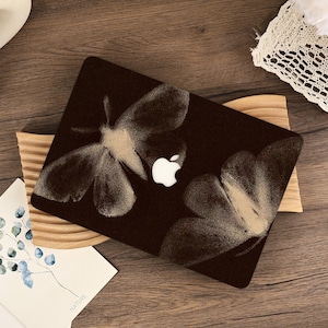 Peut inclure: Un autocollant pour ordinateur portable marron foncé orné d'un grand motif de papillon de nuit aux détails texturés et mouchetés. Le design est placé sur le couvercle, intégrant le logo Apple blanc au centre des ailes du papillon.