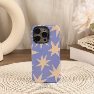 May include: A phone case with a light blue background and a pattern of beige star shapes. The case has a black camera module and is made of a smooth material. The design is simple and modern.