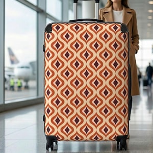 May include: A rolling suitcase with a retro pattern of repeating orange, cream, and dark brown diamond shapes. The suitcase has a black handle and black wheels. The background shows an airport terminal with an airplane.