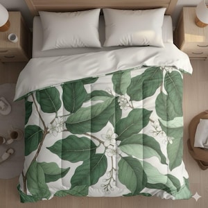 May include: A bed with a white comforter and two white pillows. The comforter features a botanical design of large green leaves and small white flowers on a white background. The bed is set on a wooden frame with two nightstands.