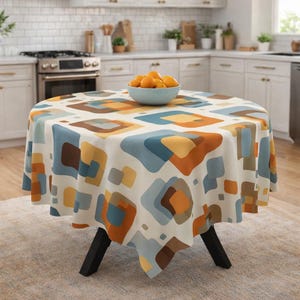 May include: A round tablecloth with a geometric pattern in shades of blue, orange, brown, and yellow. The tablecloth is draped over a black-legged table. A bowl of oranges sits on top. The tablecloth is approximately 152 cm in diameter.