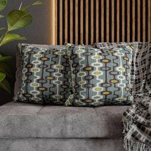 May include: Two square throw pillows featuring a repeating pattern of interconnected dark brown and white oval shapes with lime green accents on a light blue background. The pillows have a textured fabric finish and are displayed together.